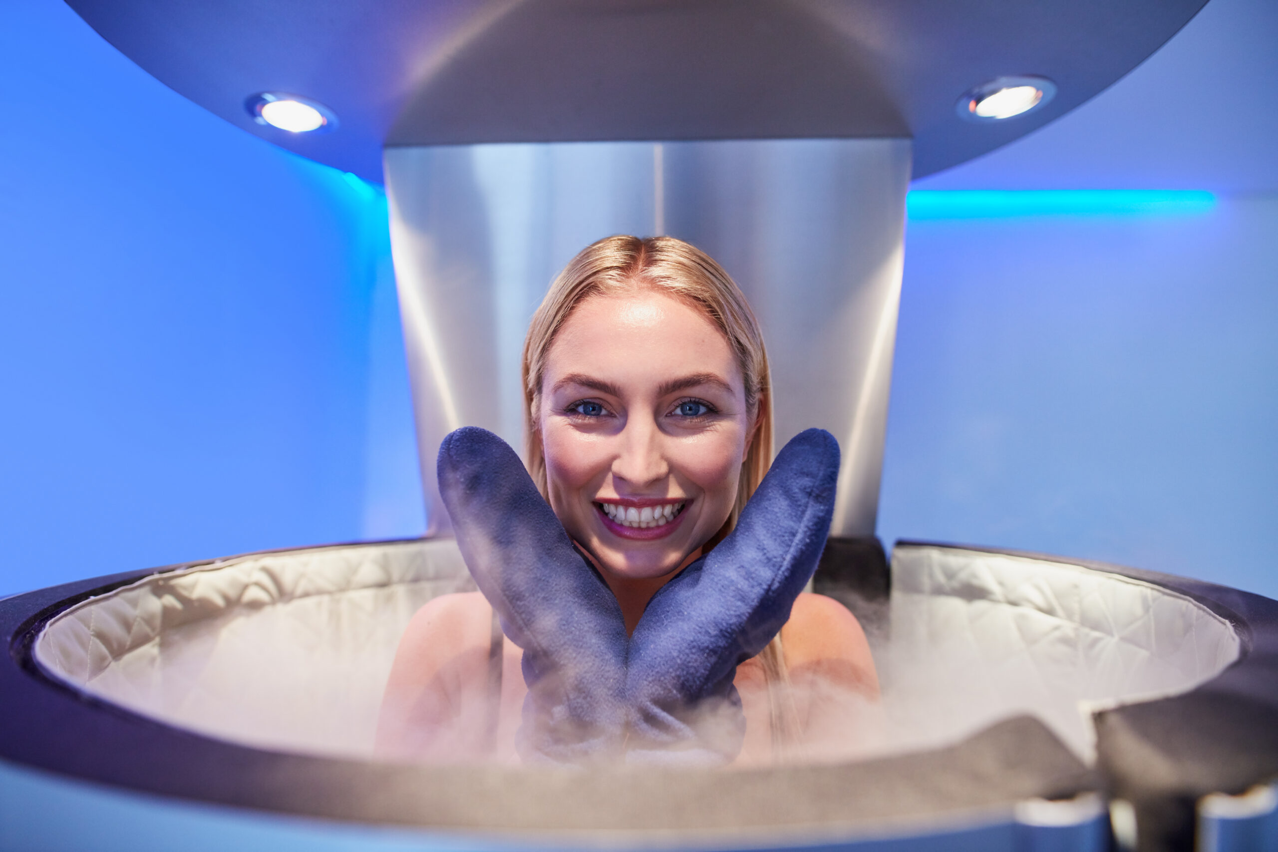 Portrait of a cute young woman in cryosauna booth for full body cryotherapy. Caucasian female in freezing chamber with nitrogen vapors.